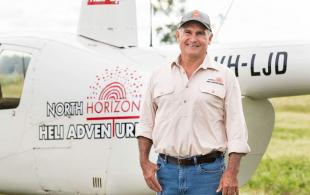 Doug McBean standing next to his helicopter for business North Horizon Heli Adventures