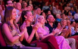 Audience members applaud during a presentation or performance in a theatre.